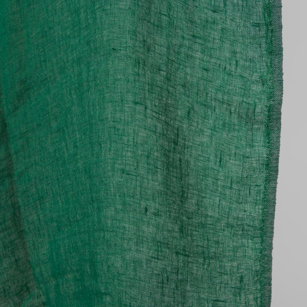 Washed linen fabric emerald green transparent close up edge view
