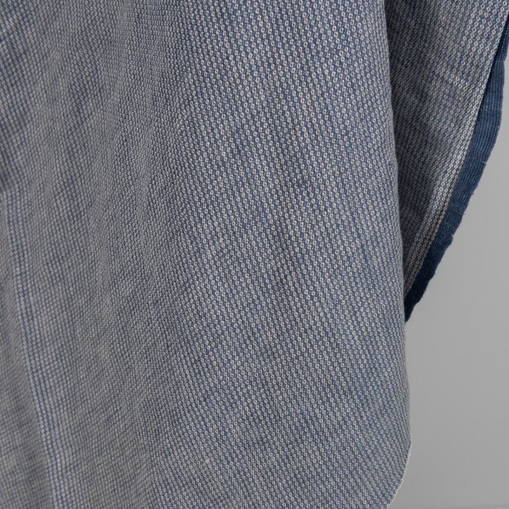 Washed linen fabric blueish grey colour small pattern close edge view