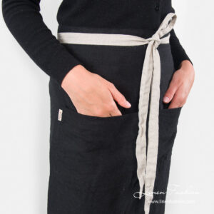 Long black apron with front pockets and waist tie close up view